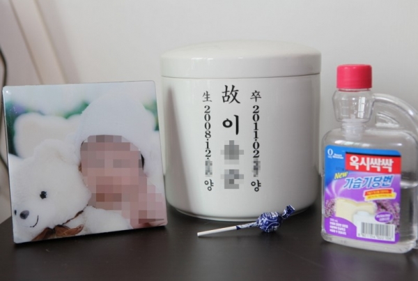 가습기 살균제로 인해 세상을 떠난 아이의 사진. 유골함 옆에는 사용했던 가습기 살균제가 놓여 있다. ⓒ환경보건시민센터